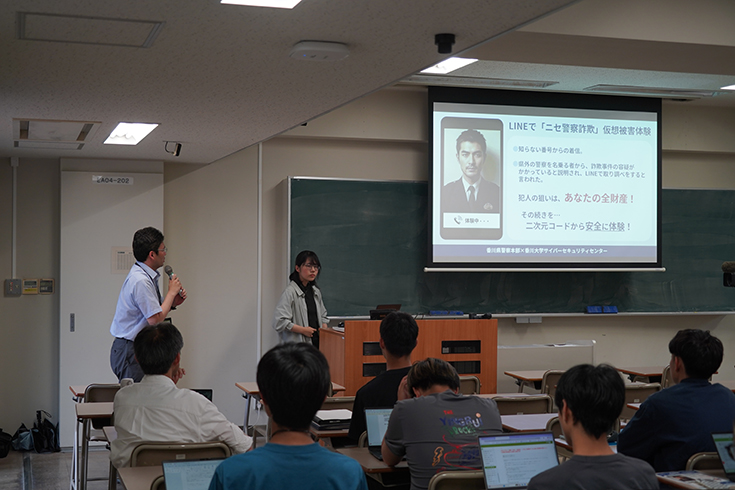「ニセ警察詐欺仮想被害体験ツール」の開発に関わった甲斐さん(創造工学部4年生)を紹介する後藤田サイバーセキュリティセンター長